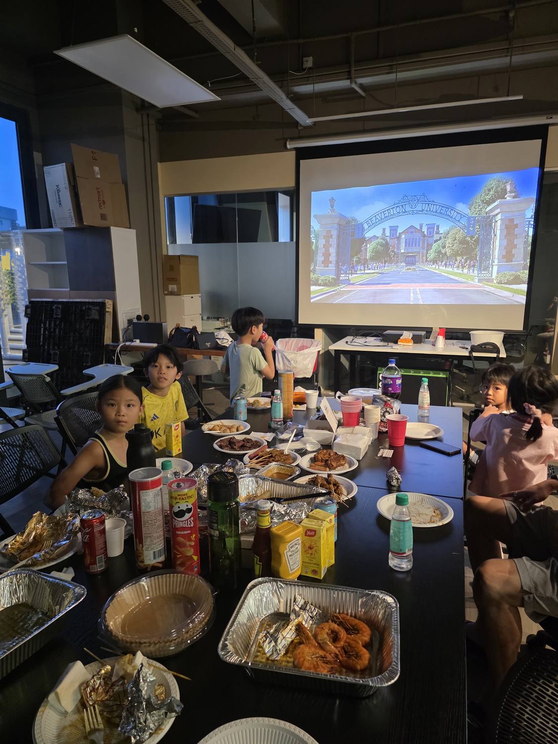 Our air-conditioned indoor function room set up with a big projector screen showing a movie, and a long table of food for a family gathering
